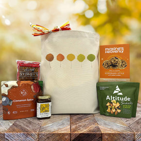 Gourmet Fall gift basket with a cranberry bar, tea, honey, trail mix, and cookies sitting on a table