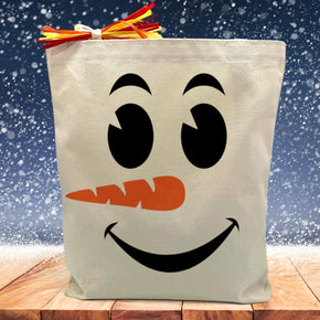 snowman face printed on a canvas tote bag sitting on a table with a snowflake background