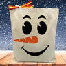 snowman face printed on a canvas tote bag sitting on a table with a snowflake background