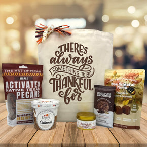 Gourmet gift basket with pecans, oatmeal, candle, and caramels sitting on a table