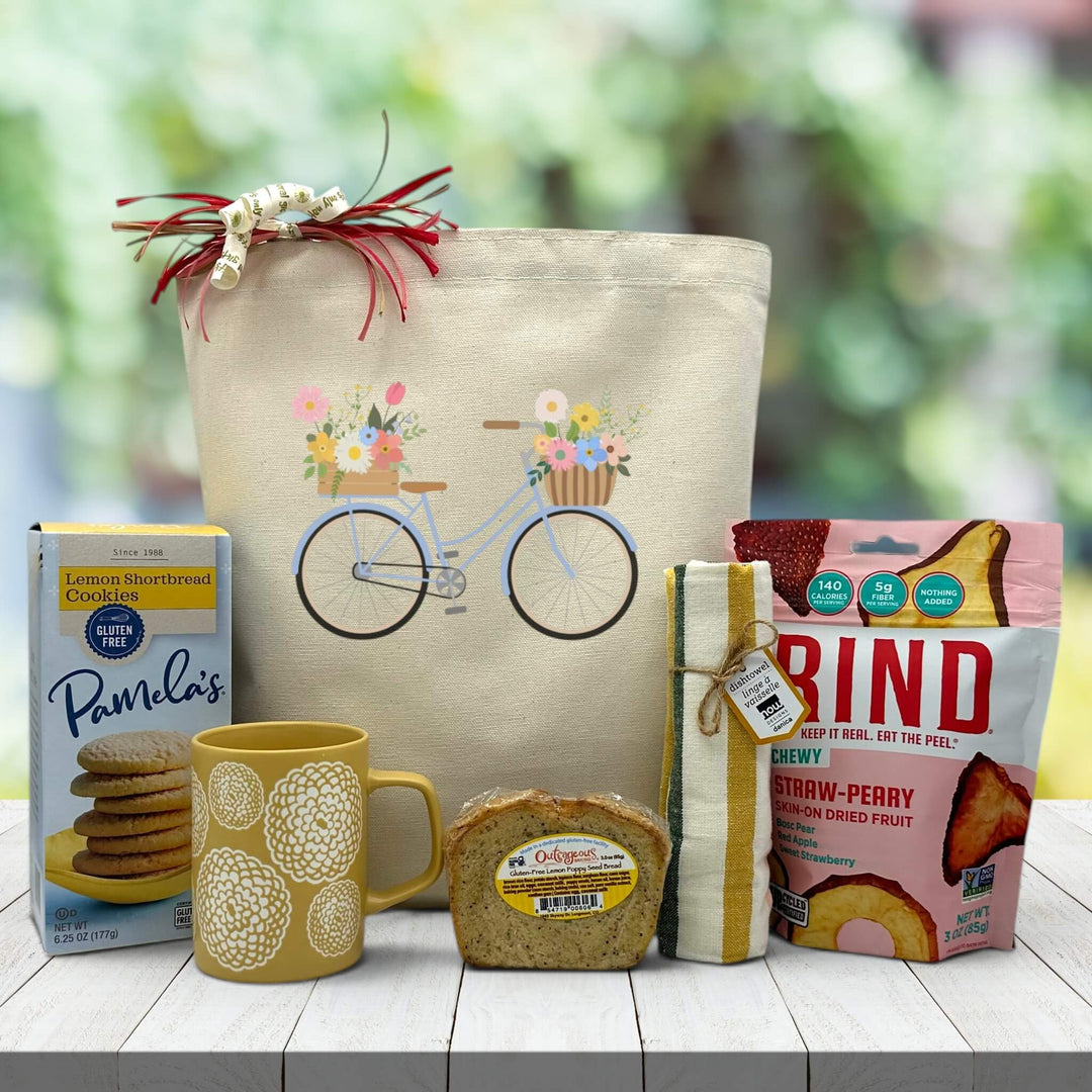 blue bicycle with flowers printed on a tote bag with snacks and a mug sitting on a wooden table