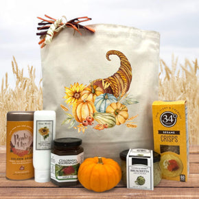 Gourmet Thanksgiving basket with tea, lotion, jam, knit pumpkin, bruschetta, and crackers sitting on a table