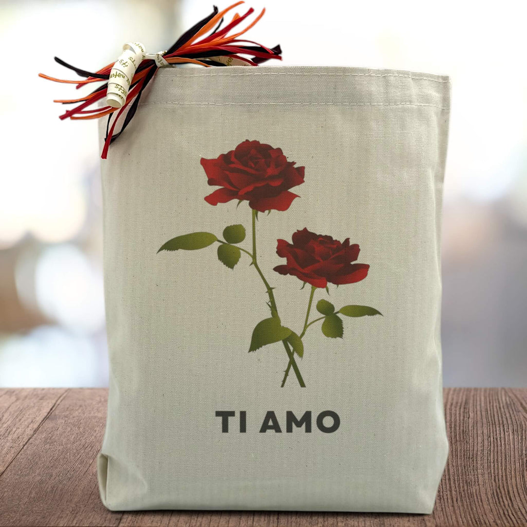 red roses with TI AMO printed on a canvas tote bag sitting on a wood table with a blurred white background