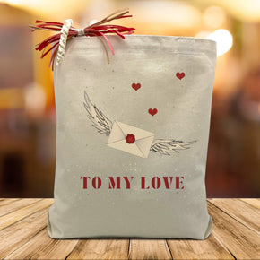 to my love with a heart flying envelope printed on a cavnas tote bag sitting on a rustic table