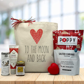 heart to the moon and back on tote bag sitting on table with tea, lotion, honey, heart squeeze and salted caramel popcorn