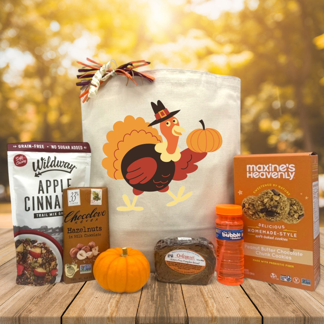 turkey designed gift basket with granola, chocolate, knit pumpkin, bread, bubbles and cookies sitting on a table