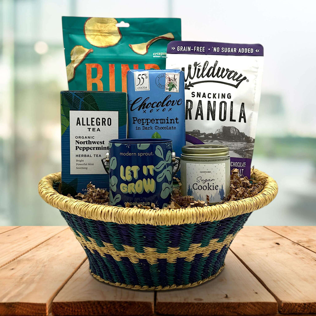 handwoven tray with apple chips, granola, chocolate bar, tea, a plant grow kit and a candle