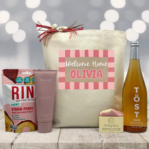 pink welcome home banner with custom name on tote bag with tropical fruist slices, lotion, soap, and tost