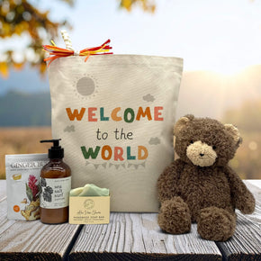 welcome to the world printed on a tote bag with ginger buds, lotion, soap and a cuddly bear sitting on a table