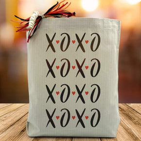 xoxo printed multiple times on a canvas tote bag sitting on a wood table