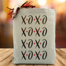 xoxo printed multiple times on a canvas tote bag sitting on a wood table