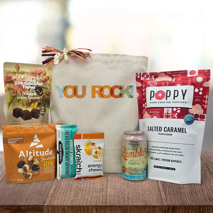 Gift bag with You Rock text surrounded by snacks including popcorn, trail mix, caramels, and grapefruit sparkling water